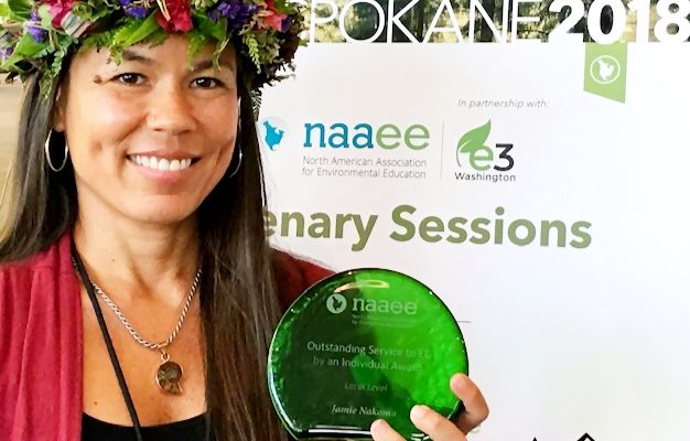 A woman proudly holds an Outstanding Service Award, smiling and celebrating her achievement.