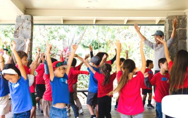 A group of children with their hands up, smiling and enjoying the moment.