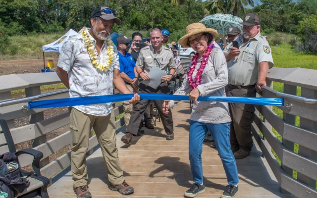 A group of people celebrating as they cut a ribbon to officially reopen the Betty Nagamine Bliss Overlook