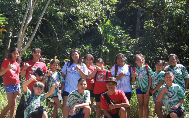 A group of young people smiling and posing together for a fun photo on a sunny day outdoors.