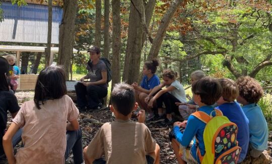 Students gather around to listen to environmental educator